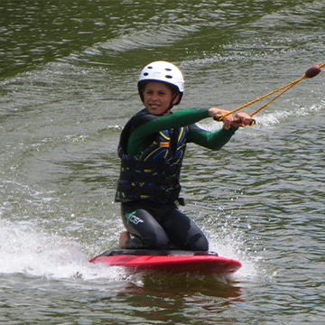 Jeune garçon sur une planche à genoux en plein virage.