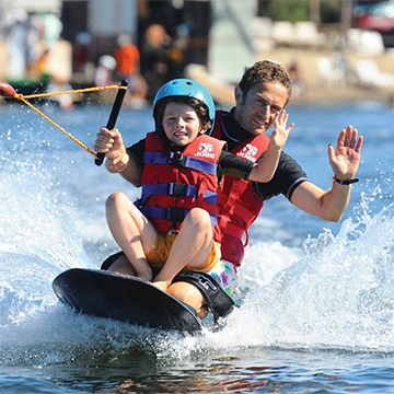 Un enfant et son papa sur une planche à genoux.